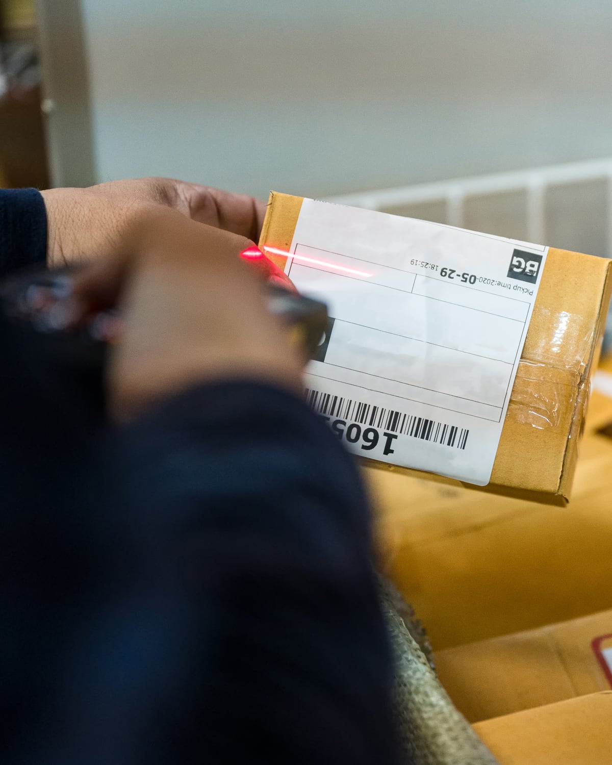 Parcel being barcode-scanned over a bin of packed ecommerce orders